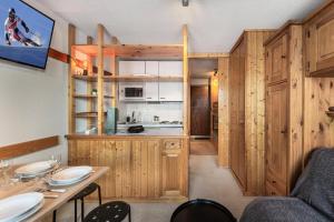 una cocina con armarios de madera, mesa y sillas en Résidence La Reine Blanche - Studio pour 4 Personnes 244, en Val Thorens