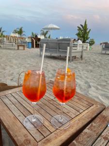 zwei Weingläser auf einem Holztisch am Strand in der Unterkunft Il Gioiello : Apt 2 pers, Clim, Piscine, Parking in Antibes