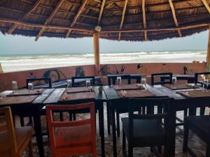 um restaurante com mesas e cadeiras e vista para o oceano em Gaal-Gui, chez Guillaume em Mboro