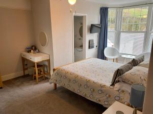 a bedroom with a bed and a desk and a window at Channel Vista Guest House in Combe Martin