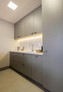 uma cozinha com armários brancos e um lavatório em Studio 403 no Vita Boulevard em Gramado