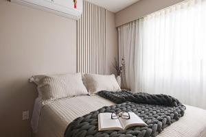um quarto com uma cama com um livro e copos em Studio 403 no Vita Boulevard em Gramado