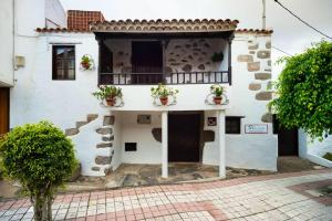 a white building with potted plants on the balcony at 5 bedrooms chalet with wifi at Firgas in Firgas
