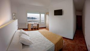Schlafzimmer mit einem Bett, einem Tisch und einem Fenster in der Unterkunft Apartamentos Costas de Bueu B in Bueu