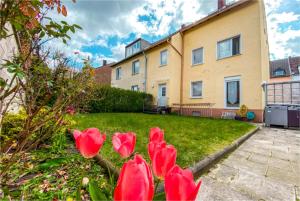 a group of red flowers in front of a house at Düsseldorf Messe and Airport, 2-bedroom Apartment with Kitchen and Garden in Am Sittardsberg