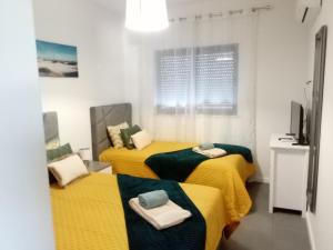 two beds in a room with yellow sheets at Alburvillage A - Apartamento Novo em Alvor in Alvor