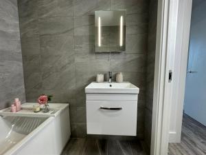 een badkamer met een wastafel, een spiegel en een bad bij Elegant One Bedroom Apartment in Swindon