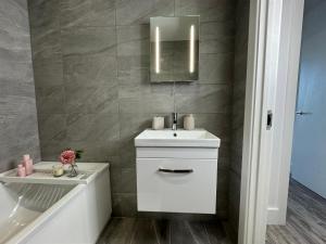 a bathroom with a sink and a mirror and a tub at Elegant One Bedroom Apartment in Swindon