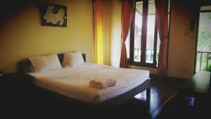 1 dormitorio con 1 cama blanca y ventana en Pai Do See Resort - ปาย ดูร์ ซี รีสอร์ท, en Pai