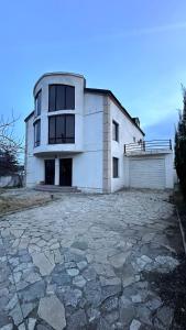 a large white house with a large stone driveway at Просторный дом в элитном районе Тбилиси in Okrokana
