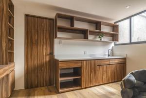 eine Küche mit Holzschränken, Spüle und Tür in der Unterkunft Eugenio SUEtes in Mexiko-Stadt