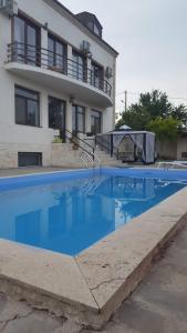 a swimming pool in front of a house at Просторный дом в элитном районе Тбилиси in Okrokana