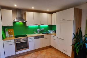 a kitchen with white cabinets and a green wall at Ferienwohnung in Weyregg am Attersee in Weyregg