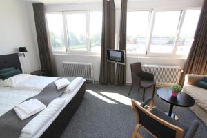 um quarto de hotel com uma cama, um sofá e uma televisão em Banegaardshotellet em Vojens