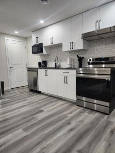 a kitchen with white cabinets and stainless steel appliances at Trendy 2-Bed Oasis Awaits! in Calgary