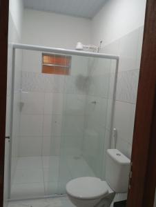 a white bathroom with a toilet and a shower at Chalés Passagem do Canto in Barreirinhas