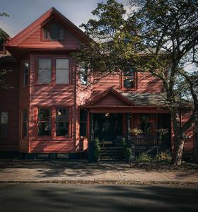 una casa roja con un árbol delante en Dvele Inn en San Juan de Terranova
