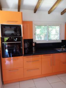 - une cuisine avec des armoires orange et un four micro-ondes dans l'établissement Villa des fleurs, à Pointe-Noire