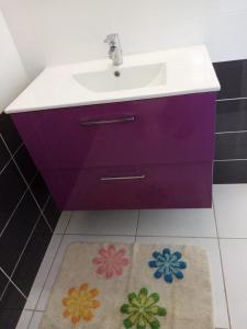 a bathroom with a purple sink and a rug at Villa des fleurs in Pointe-Noire