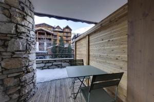 een patio met een tafel en stoelen op een houten terras bij Residence Telemark - 2 Pièces pour 4 Personnes 104 in Val dʼIsère