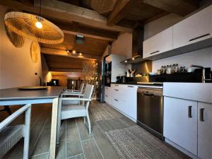 una cucina con armadi bianchi, tavolo e sedie di Chalet Aster - 4 Pièces pour 6 Personnes 444 a Saint-Marcel