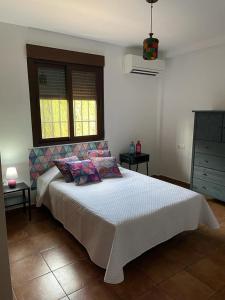 a bedroom with a white bed and two windows at Villatrajín in Otura