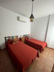 two beds in a room with red sheets at Villatrajín in Otura