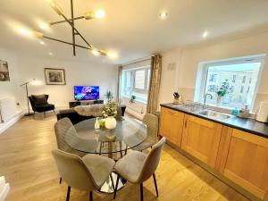 uma cozinha e sala de estar com uma mesa de vidro e cadeiras em Kiwi Tree Serviced Apartment em Cambridge