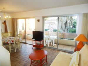 een woonkamer met een televisie en een woonkamer met een tafel bij 3 pièces 6 pers à 2 pas de la plage et du centre ville in Cavalaire-sur-Mer