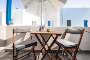 a wooden table with two chairs and an umbrella at Lefkes Studios in Naxos Chora