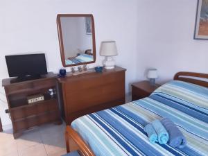 a bedroom with a bed and a dresser with a mirror at Appartamento al mare in Porto Santo Stefano