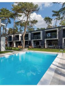 a swimming pool in front of a house at Prestige House Apartament - 2 sypialnie z ogródkiem i basenem in Pobierowo
