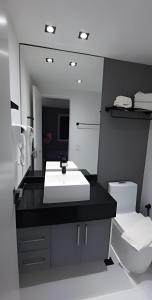 a bathroom with a sink and a toilet and a mirror at Paulista Premium Flat in São Paulo