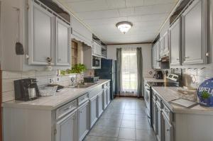 a large kitchen with white cabinets and a tile floor at Silver Creek Getaway with Fireplace - 12 Mi to Lake in Prentiss