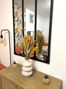 a vase on a dresser in front of a mirror at L’émeraude - T2 en plein coeur de Dinan in Dinan