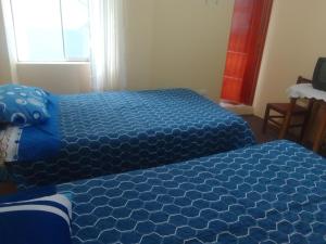 1 dormitorio con 2 camas y sábanas azules en killa andina inn, en Puno