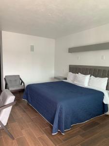 um quarto com uma cama azul e uma cadeira em HOTEL LOS PORTALES CHIGNAHUAPAN em Chignahuapan