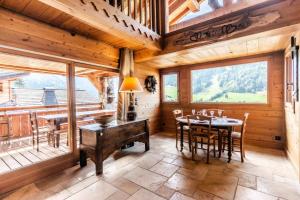 ein Esszimmer mit einem Tisch und Stühlen sowie einem großen Fenster in der Unterkunft Chalet As De Coeur - Chalets pour 14 Personnes 224 in Morzine