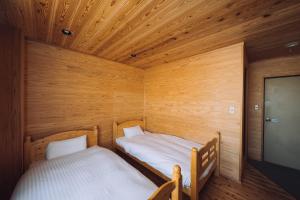 a room with two beds in a wooden room at Noasobi lodge - Vacation STAY 80823v in Arao
