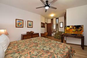 een slaapkamer met een bed en een plafondventilator bij Kuleana Resort #105 in Kahana