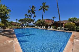 een zwembad met stoelen en palmbomen bij Kuleana Resort #105 in Kahana