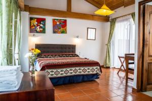 1 dormitorio con 1 cama y 1 mesa en Hostal Riviera Sucre, en Otavalo