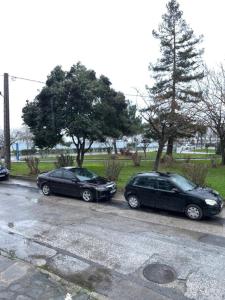 dos autos están estacionados en un estacionamiento en Thomais Guesthouse, en Kavala