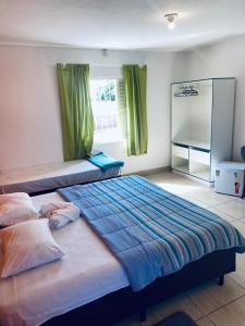 a bedroom with two beds with green curtains and a mirror at Hotel Beira Rio Guararema in Guararema