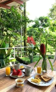 a wooden table with breakfast foods and orange juice at Glamping Naioth in Guápiles