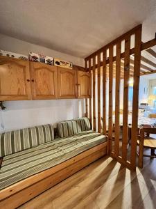 1 dormitorio con 1 cama, armarios de madera y mesa en Résidence Les Glovettes - Studio pour 6 Personnes 234 en Villard-de-Lans