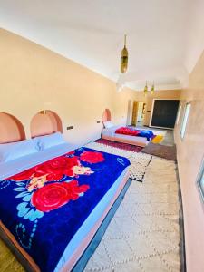 een slaapkamer met 2 bedden en een blauwe deken bij Gîte d'étape Tamaloute in Bou Drarar