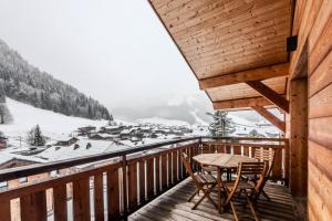 a table and chairs on a balcony with a snow covered mountain at Chalets Brunes - 3 Pièces pour 6 Personnes 544 in Morzine
