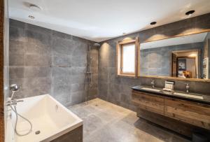y baño con bañera, lavabo y espejo. en Résidence Bois De L'abbaye - Chalets pour 12 Personnes 484 en Le Pra