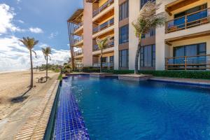 a hotel with a swimming pool next to a beach at Beach front Varandas Do Mar in Cumbuco